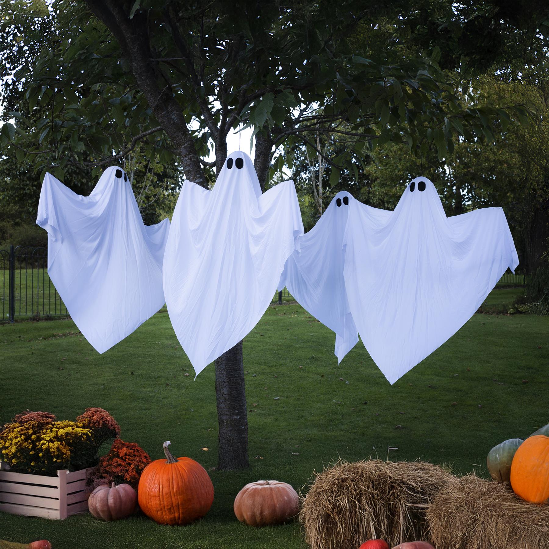LED Hanging white ghost figures, attached from a tree, in a garden at night. 