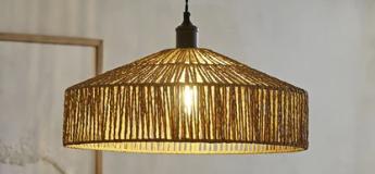 Rattan Ceiling Light against white wall, black wire and an oak skirten board