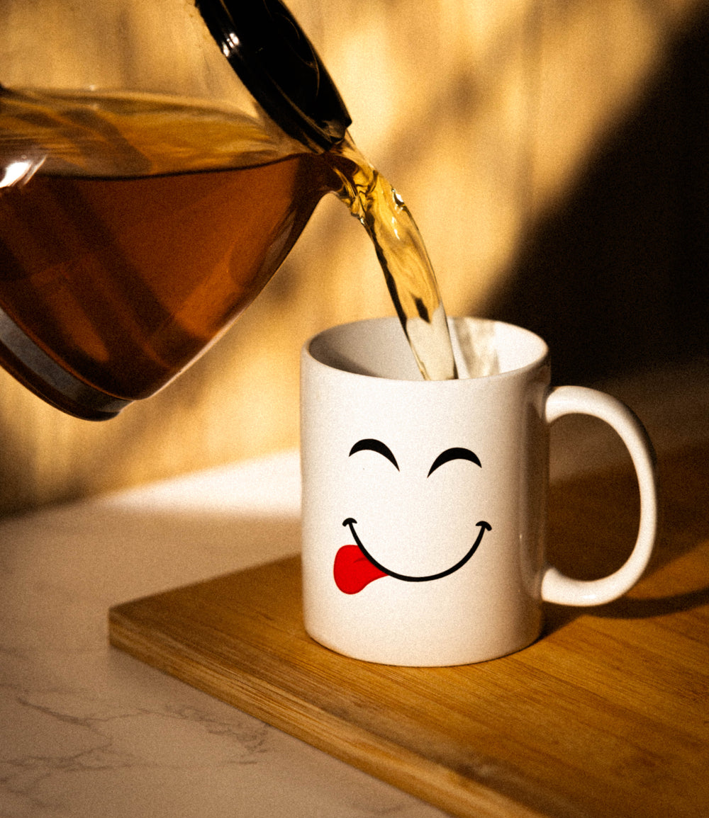 A set of white porcelain mugs with various playful facial expressions and heart symbols designed on them.