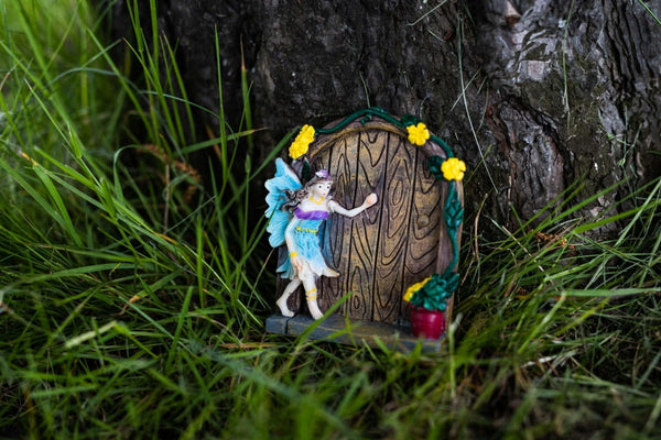 Miniature fairy doors displayed at the base of a tree