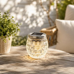 Solar-powered outdoor lantern on a wooden table with plants and furniture in the background