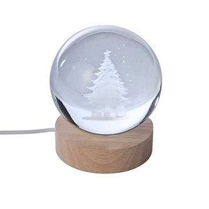 Clear glass crystal ball light with etched Christmas tree design, natural wooden base and USB power cable on a white background.