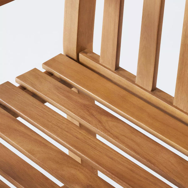 Close-up detail of a wooden slatted chair or bench with a warm medium-brown finish and visible wood grain, set against a plain white background.