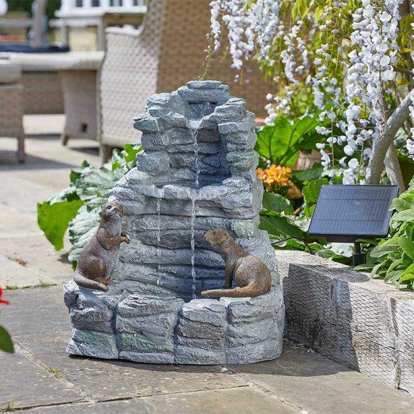 Outdoor garden fountain with stone design and two animal figures, featuring a solar panel.