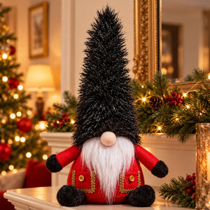 A festive Christmas gnome decoration with a tall black glittery hat, red outfit, white beard, and black feet, displayed on a mantel in a warmly lit holiday room.
