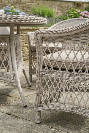 Wicker outdoor furniture set with cushions on a stone patio.