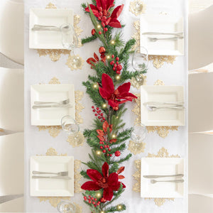 Decorative Christmas table setting with a garland featuring red flowers and greenery.