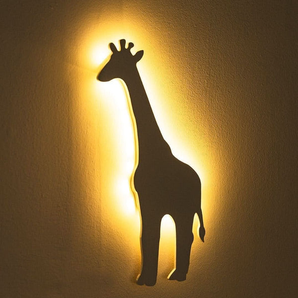 Giraffe-shaped wall light casting a warm glow on a beige wall