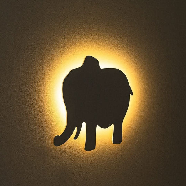 Wall light fixture with an elephant silhouette on a dark background
