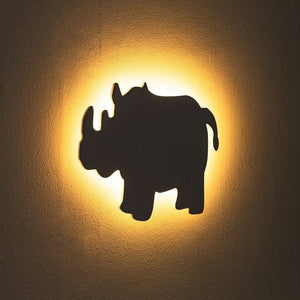 Black silhouette of a rhino on a textured wall with a warm glow
