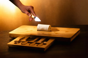 Person using a flashlight on a wooden cutting board with a rolled-up paper towel.