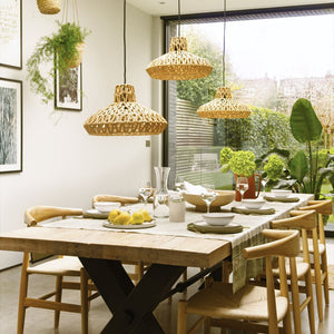 Dining room with wooden table, chairs, and wicker pendant lights.