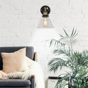 Wall-mounted light fixture above a gray sofa with pillows and a plant in a room with white brick walls.