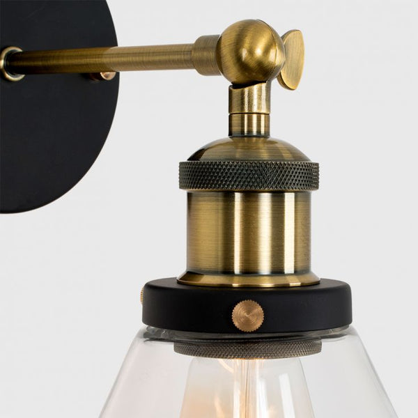 Close-up of a wall-mounted light fixture with brass and black design on a white background