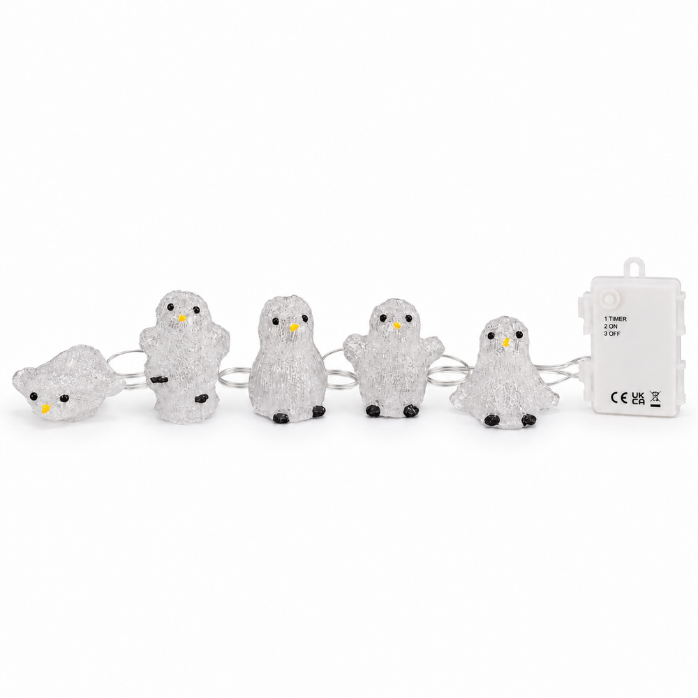 Five glowing penguin-shaped string lights arranged across a dark wooden mantel