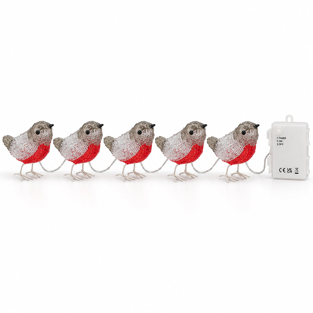 Lighted robin string lights shaped like small birds, glowing with red and white lights, arranged on a dark wooden dining table in a decorated holiday home setting.