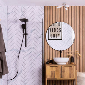 Bathroom interior with wooden vanity, round mirror, and shower setup.