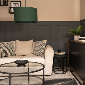 Modern living room with a beige sofa, decorative pillows, and a dark green lamp.
