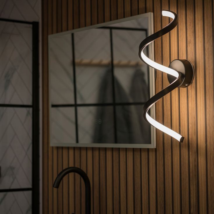 Modern wall-mounted light fixture in a bathroom setting with a mirror and shower area.