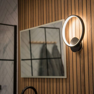 Modern wall-mounted light fixture on a wooden wall with a mirror in the background