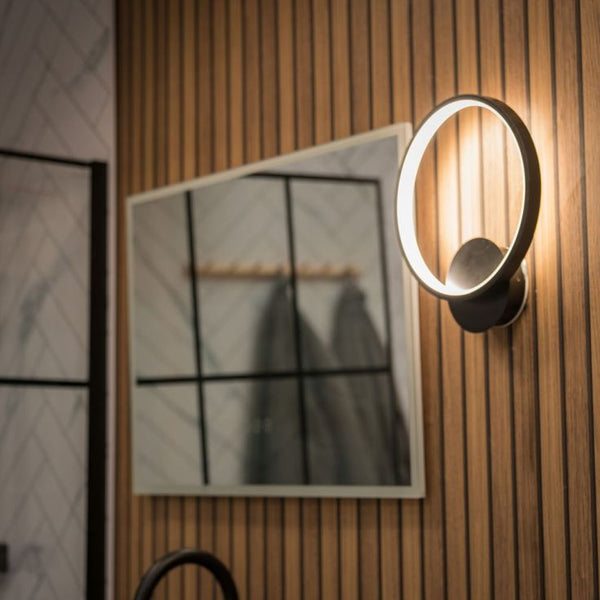Modern wall-mounted light fixture on a wooden wall with a mirror in the background
