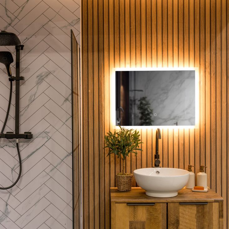 Bathroom with wooden slat wall, illuminated mirror, and white sink.