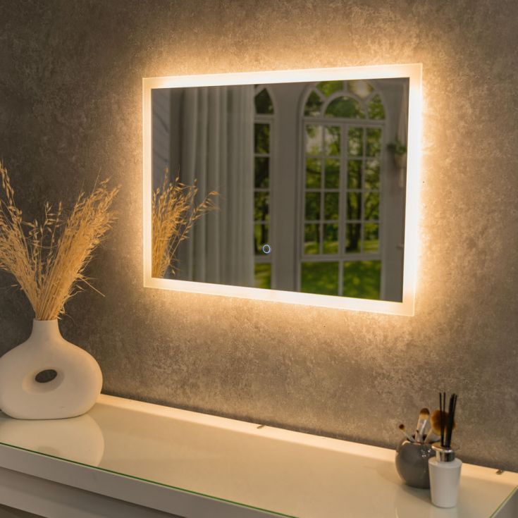 Bathroom with wooden slat wall, illuminated mirror, and white sink.