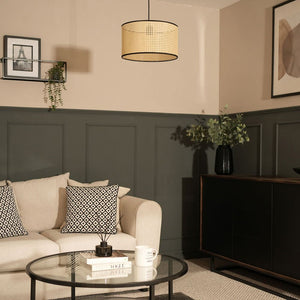 Living room with beige sofa, round glass coffee table, and dark paneling.