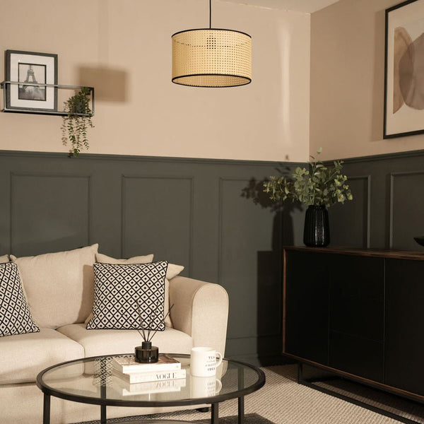 Living room with beige sofa, round glass coffee table, and dark paneling.
