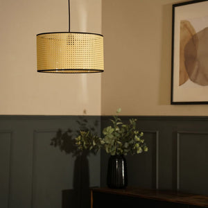 Decorative pendant light with woven shade in a room setting.