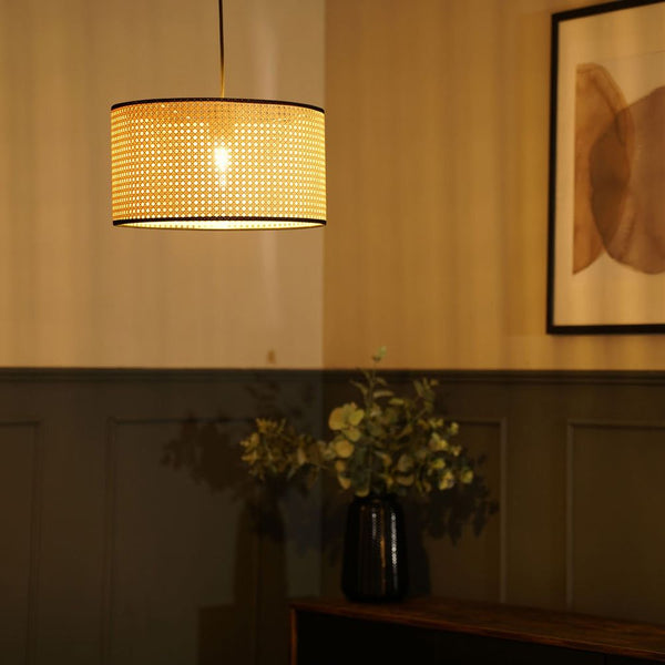 Decorative lampshade hanging above a vase with flowers on a wooden surface.