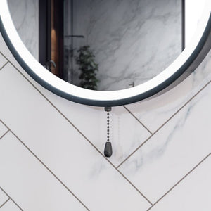 Round mirror with a pull chain on a tiled wall