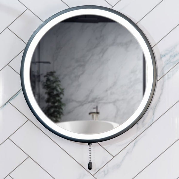 Round wall mirror with black frame on a tiled bathroom wall