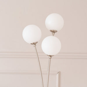 Modern floor lamp with three white spherical lights on a neutral background