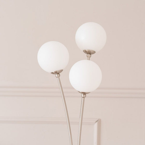 Modern floor lamp with three white spherical lights on a neutral background