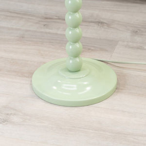 Green lamp with a cylindrical design on a wooden floor