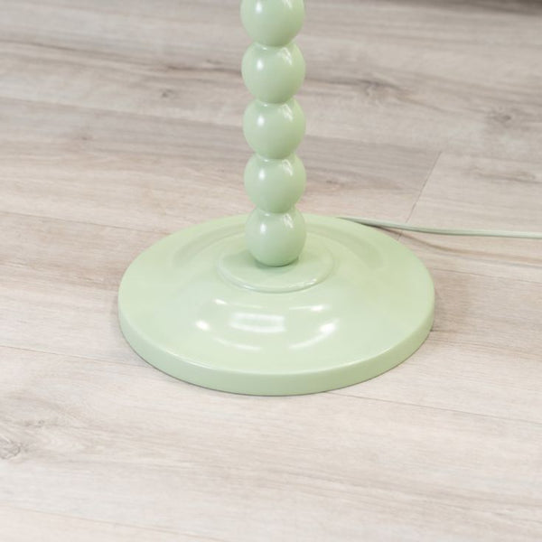 Green lamp with a cylindrical design on a wooden floor