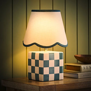 Table lamp with checkered base and scalloped shade on a wooden surface.