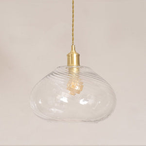 Clear glass pendant light with gold fixture on a plain background