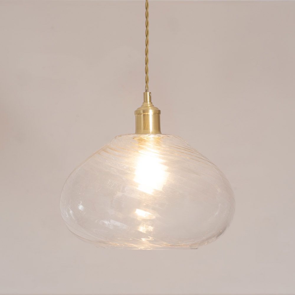 Clear glass pendant light with gold fixture on a plain background