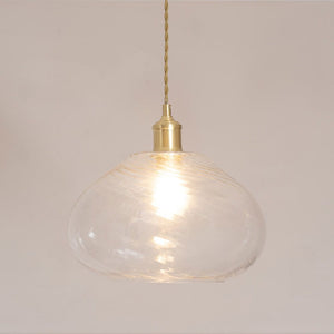 Clear glass pendant light with gold fixture on a plain background