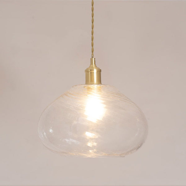 Clear glass pendant light with gold fixture on a plain background