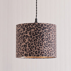Leopard print lampshade hanging against a striped wall.