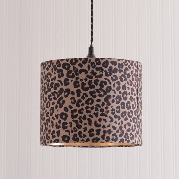 Leopard print lampshade hanging against a striped wall.