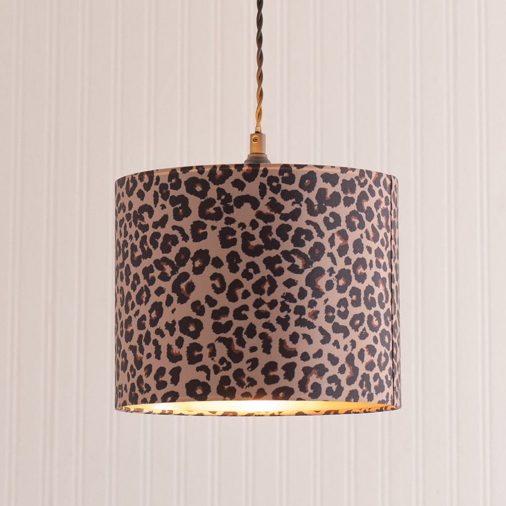 Leopard print lampshade hanging against a striped wall.