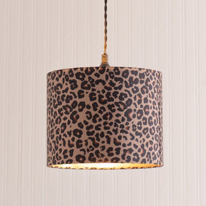 Leopard print lampshade hanging against a striped wall.