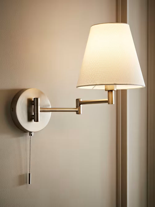 Wall-mounted lamp with a white shade on a beige wall