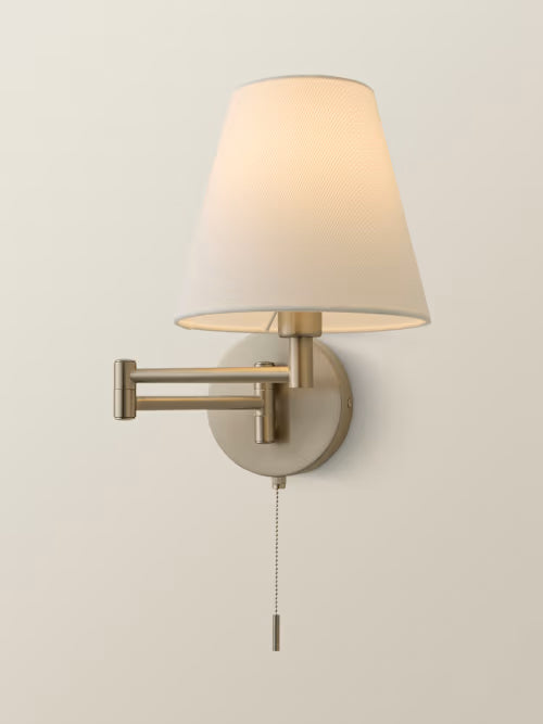 Wall-mounted lamp with beige shade and pull chain on a light gray background