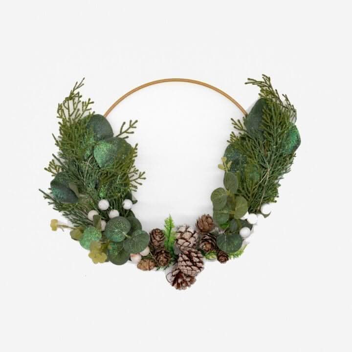 Sage foliage hoop decorated with pinecones and white berries