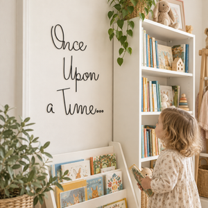 A young child with blonde hair stands in a cozy nursery or children's room beside a white bookshelf and a wall sign that reads 'Once Upon a Time.